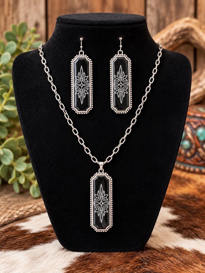 Black and silver engraved rectangular pendant necklace and matching drop earring set displayed on a black jewelry bust