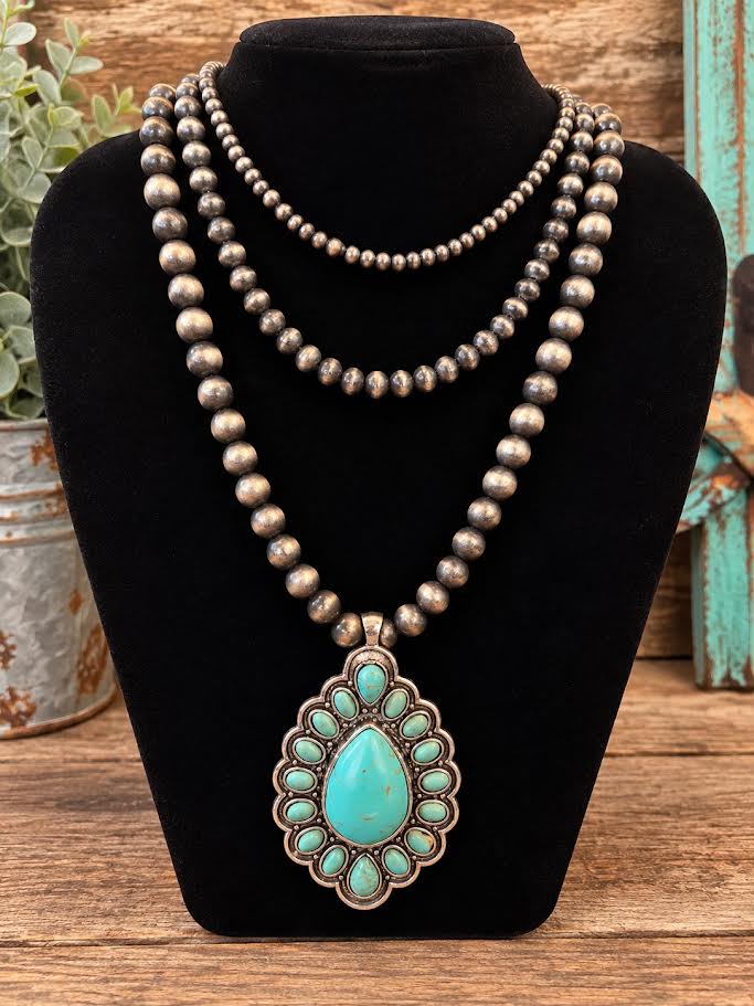 Layered Navajo pearl necklace with turquoise cluster teardrop pendant on black jewelry bust